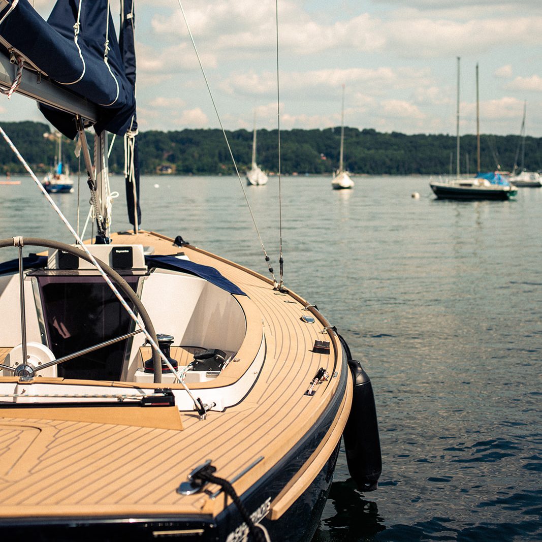 Segelyacht im Wasser, umgeben von anderen Booten und einer ruhigen Landschaft.