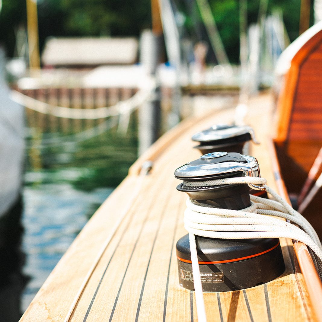 Bootsdeck mit Winschen und Seilen, ruhig im Wasser reflektiert.