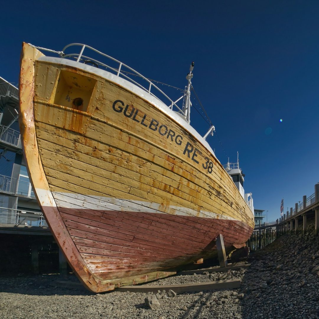Alter Holzschiff mit der Aufschrift "Gullborg RE-38", am Ufer liegend.