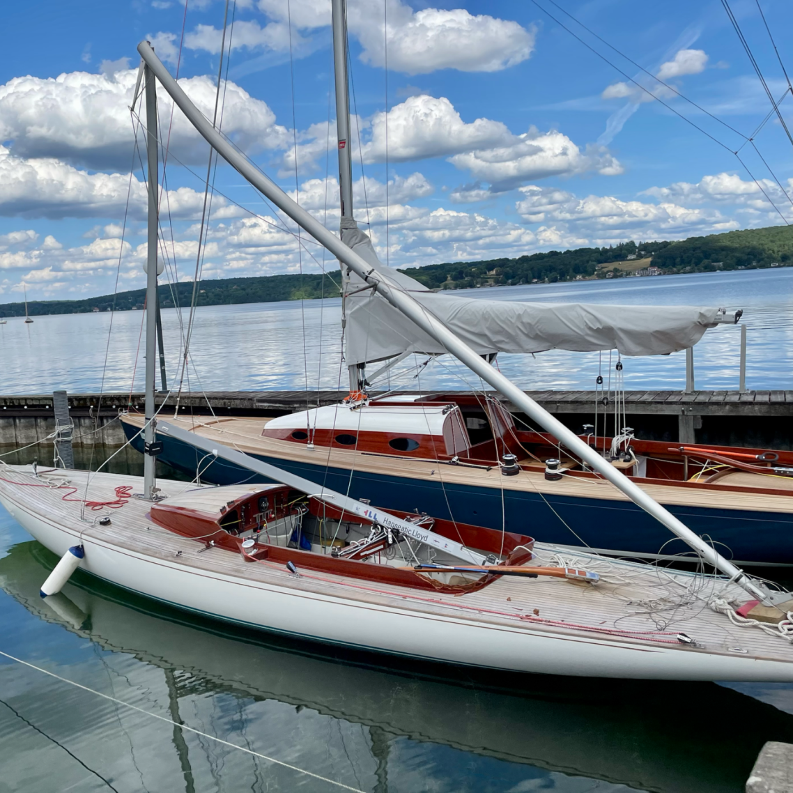 Zwei Segelboote im Wasser mit blauem Himmel und weißen Wolken im Hintergrund.